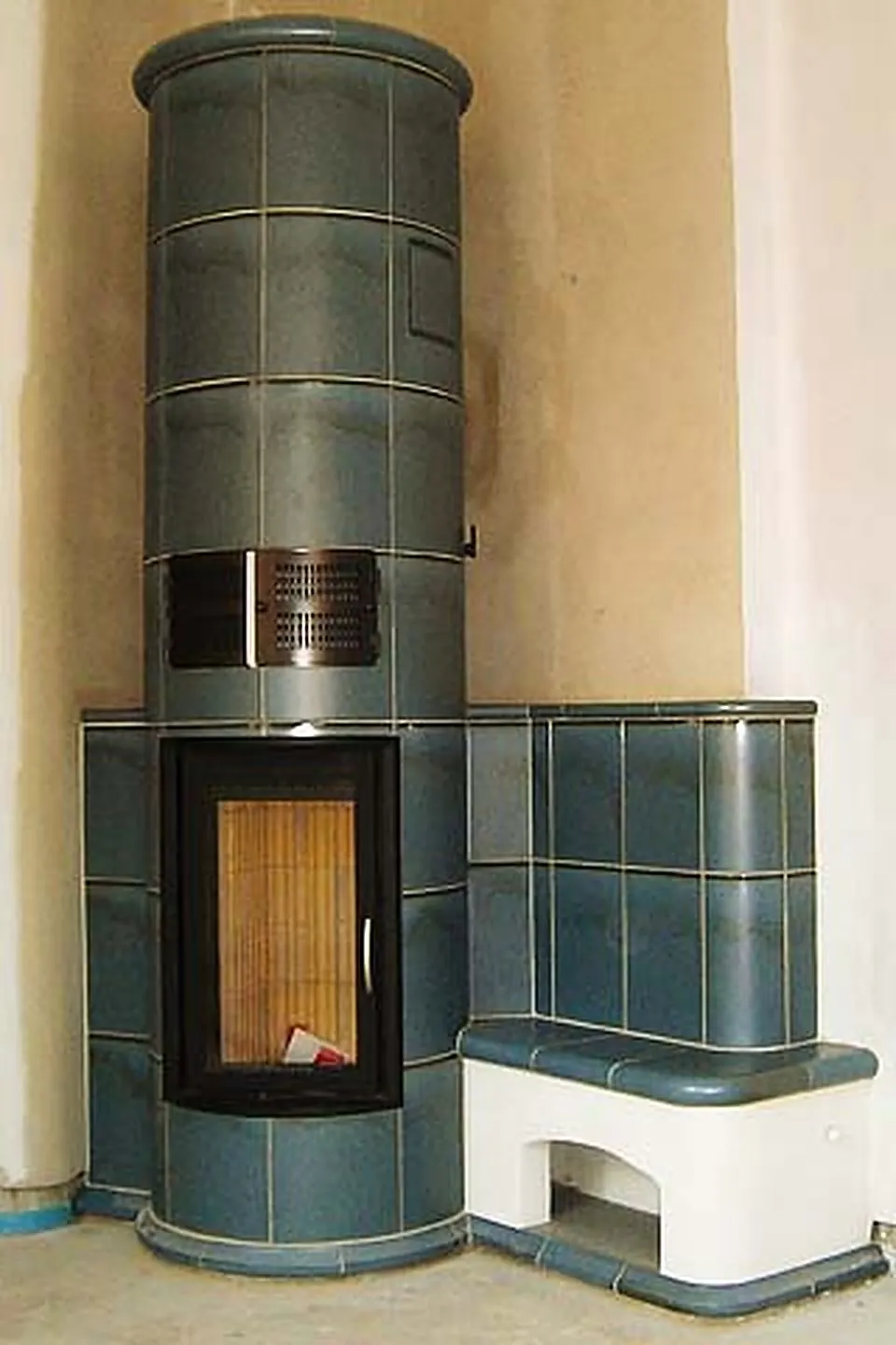 Kachelofen mit blaugrauen Kacheln und offenem Feuerraum