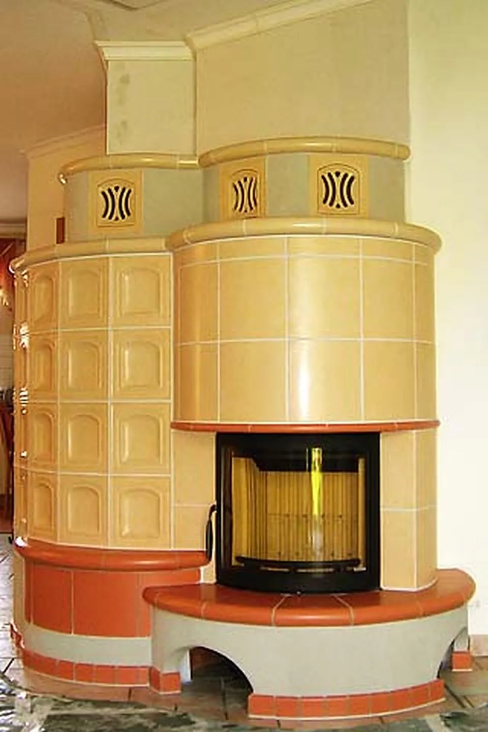 Cremefarbener Kachelofen mit Ornamentkacheln und rotem Sockel
