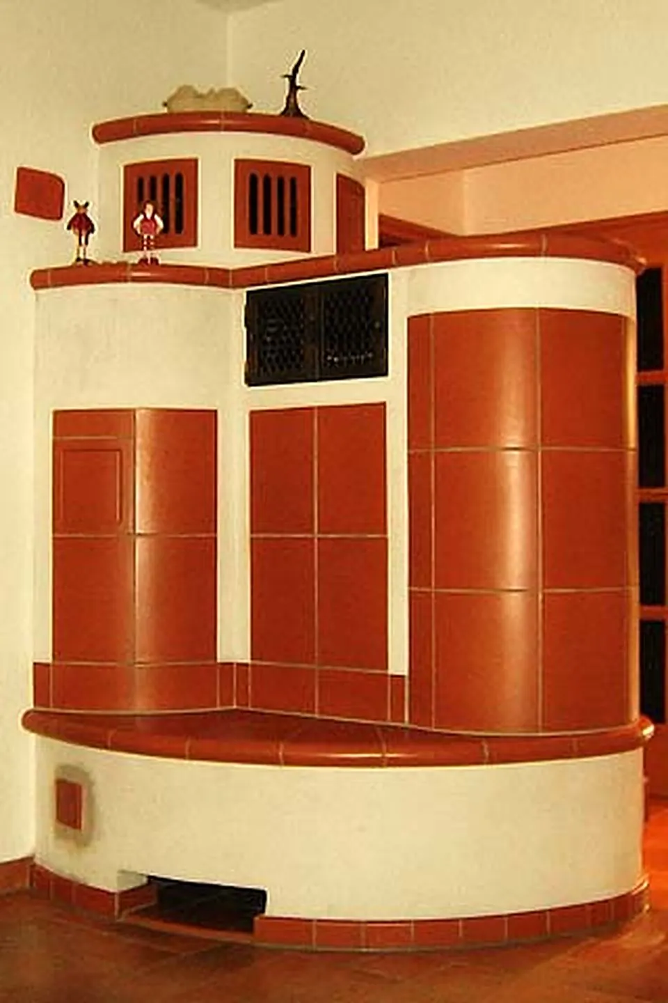Terracottafarbener Kachelofen mit Treppenaufbau