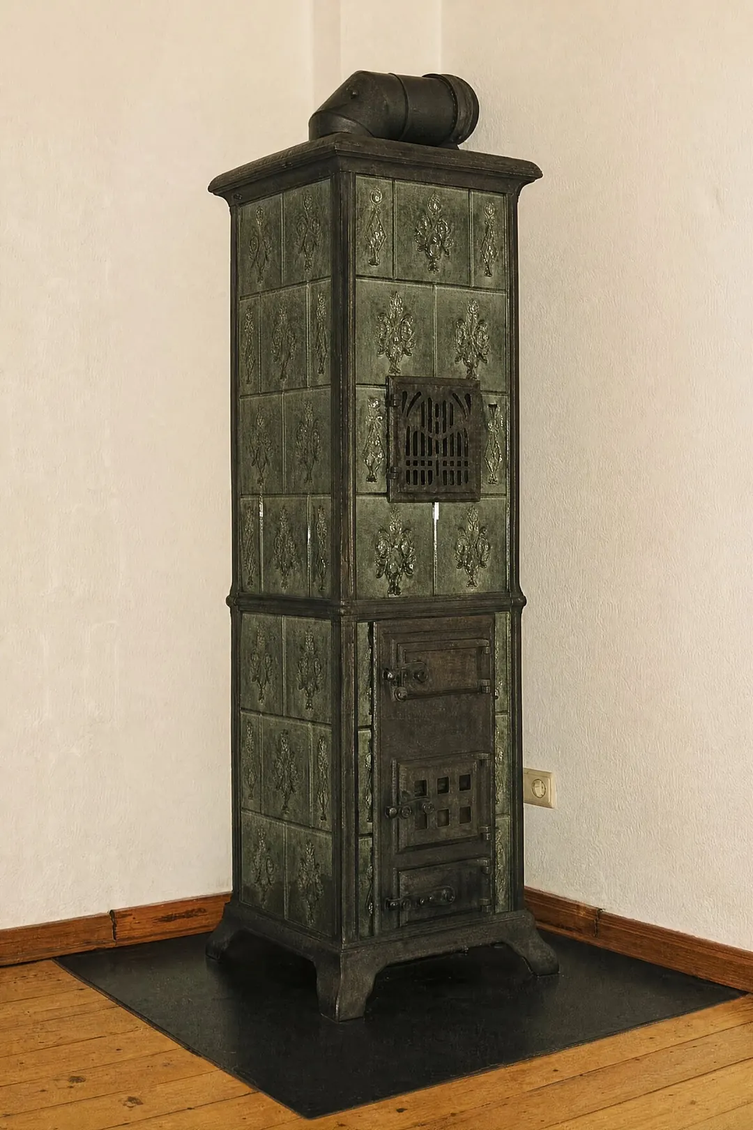 Historischer gusseiserner Kaminofen mit grün glasierten Ornamentkacheln